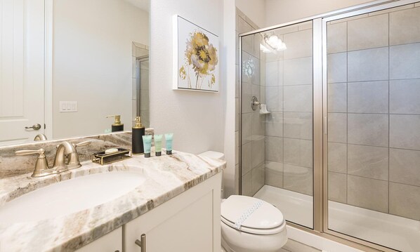 A bathroom with a marble sink, a toilet, and a glass shower enclosure. - South-Facing Pool Villa with Fire Pit Near Disney (Kissimmee)