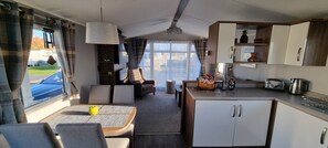 Enjoy a compact living space with a kitchenette, dining area, and large window offering a view of the outdoors.