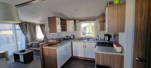Compact kitchenette with stove, sink, and appliances, plus a cozy seating area with a cushioned bench.