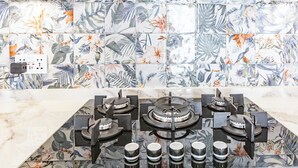 A kitchen with a tiled backsplash featuring tropical leaf and bird designs, a gas stove with four burners, and an Amazon power strip. - Casa Sandra, Newly renovated traditional Andalucian townhouse (Competa)