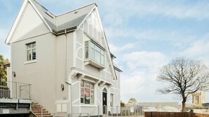 A two-story building with a gabled roof and a balcony on the second floor. - Luxury Central Apartment With Car Parking (St Ives)