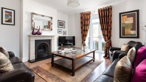 A living room with a fireplace, a television, and a coffee table. - Luxury Central Apartment With Car Parking (St Ives)