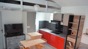 Een compacte keuken met een televisie, een eettafel en een rode kast.