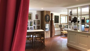 Una habitación con una mesa de comedor, sillas, un mueble de madera con obras de arte y una cortina roja.