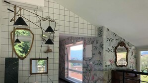 Una habitación amplia con pared de azulejos, un espejo grande y un aparador de madera.