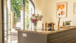 Eine moderne Küche mit einer großen Kochinsel, einem Einbauofen und Blick durch eine Glastür in einen Außenbereich.
