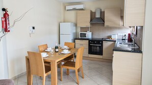 A compact kitchen with a dining area, equipped with a refrigerator, microwave, oven, and sink.