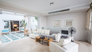 A spacious living room with a sofa, coffee table, and a TV. There is a sliding glass door leading to an outdoor area. - Luxury 5 Bedroom Villa with Private Pool, Protaras Villa 1272 (Protaras)
