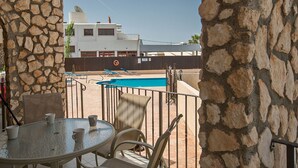 A stone wall, a pool, and a building with a satellite dish in the background. - Picture This (Ayia Napa)