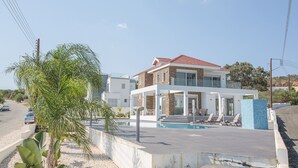 A modern two-story house with a swimming pool, a covered patio, and a view of the road. - Luxury 5 Bedroom Villa with Private Pool, Protaras Villa 1230 (Protaras)