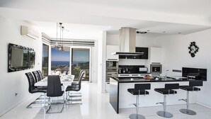 A modern kitchen with a central island, bar stools, and a dining area with a view.