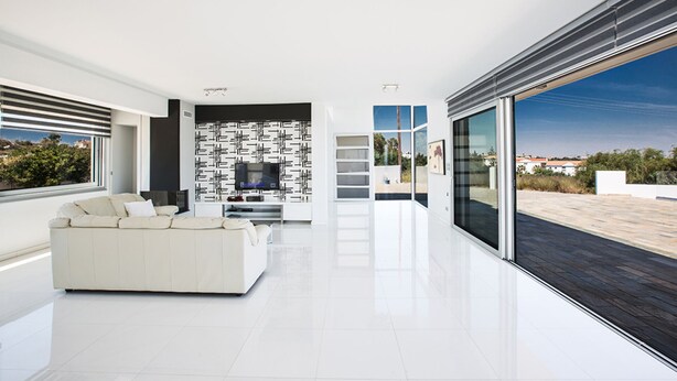A modern living room with a white sofa, a TV, and a patterned wall.
