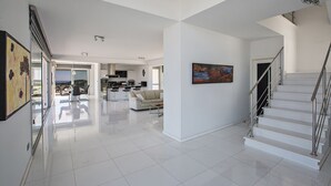 A spacious living area with a kitchen, a staircase, and a large window overlooking a scenic view.