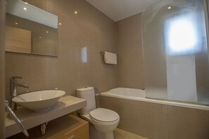 Et badeværelse med stor vask, toilet og badekar.