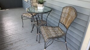 A glass-top table with two wicker chairs and a potted plant on a wooden deck. - Summer And Track Season Rental (Saratoga Springs)
