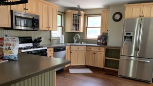 A kitchen with wooden cabinets, stainless steel appliances, and a wooden floor. - Summer And Track Season Rental (Saratoga Springs)