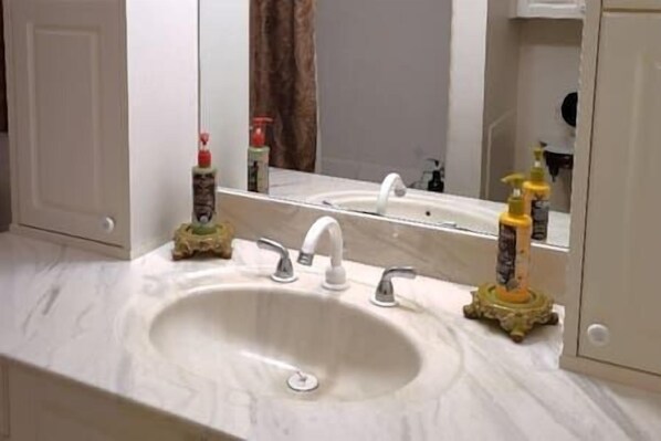 A bathroom with a white sink, two faucets, and a mirror above it.