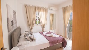 A bedroom with a bed, curtains, an air conditioning unit, and a view of the outside. - How to Rent Your Own Private Luxury Holiday Villa in Protaras for Less than Basic Hotel (Protaras)