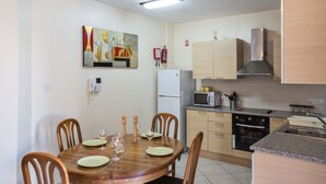 Cocina compacta con una mesa de comedor para cuatro personas, microondas, horno y refrigerador.
