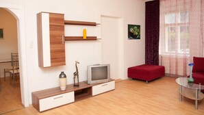 Un salon moderne avec un téléviseur posé sur un meuble en bois, un canapé rouge et une table en verre.