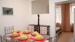 Un coin repas avec une table dressée pour quatre personnes, un petit meuble et un tableau accroché au mur.