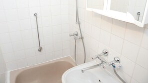 Une salle de bain équipée d’une baignoire, d’un lavabo, d’une douche et d’une barre d’appui.