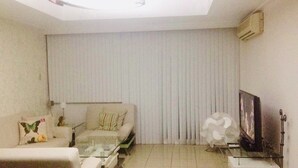 A living room with a sofa, a coffee table, a TV, and a radiator. - 1-BR Robinson Place Residences, 68 sqm. Condo (Ermita Manila)