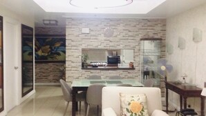 A compact living space with a dining area, a kitchen with a built-in stove, and a seating area with a sofa and a chair. - 1-BR Robinson Place Residences, 68 sqm. Condo (Ermita Manila)