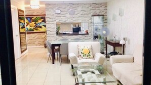 A living room with a glass coffee table, a sofa, and a dining area with a table and chairs. - 1-BR Robinson Place Residences, 68 sqm. Condo (Ermita Manila)