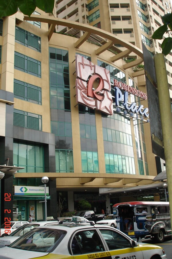 A building with a large sign for Robinsons Place, a RobinsonsBank, and a taxi stand.