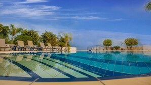 Una piscina con sillones de descanso y palmeras.
