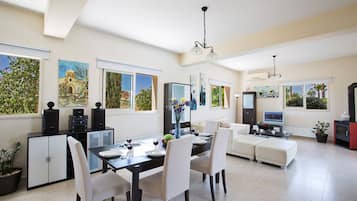 Una sala moderna con comedor, ventanas amplias y obras de arte en las paredes.