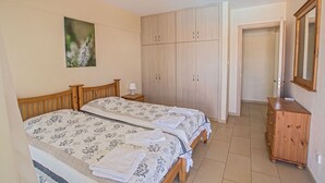 Ein Schlafzimmer mit zwei Betten, einem Kleiderschrank, einem Spiegel und einem Bild an der Wand.