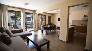 Una sala de estar moderna con un sofá, una mesa de comedor y una zona de cocina con lavadora.