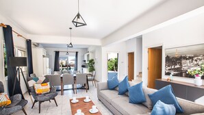 Ein modernes Wohnzimmer mit Sofa, Sesseln, einem Couchtisch und einem Essbereich.