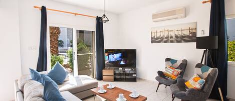 A living room with a sofa, two armchairs, a coffee table, and a television.