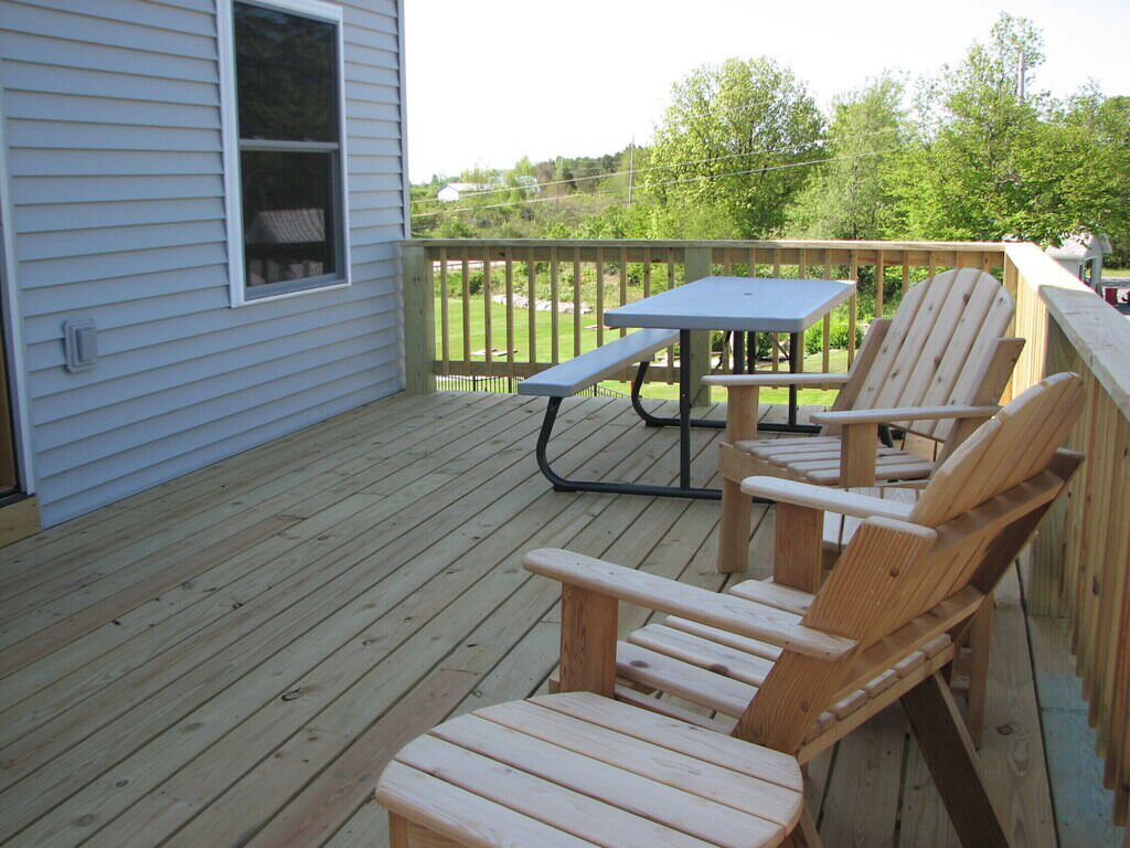 Un pontile in legno con tavolo da picnic e poltrone Adirondack.