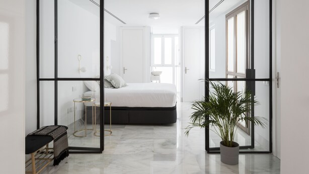 A modern bedroom with a bed, bedside tables, and a potted plant. - Design apartment (Sevilla)