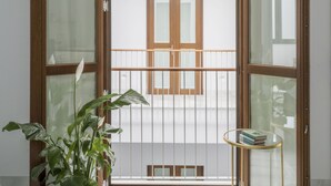 A room with a sliding glass door leading to a balcony, a potted plant, and a small round table with books. - Design apartment (Sevilla)