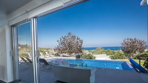 Ein Poolbereich im modernen Stil mit Meerblick, einer Liege und einem kleinen Tisch mit Getränken.