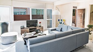 Un salon moderne avec un canapé gris, une table basse, un téléviseur et une lampe.