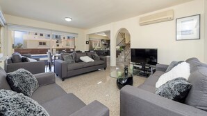Un salón moderno con sofás grises, una mesa de centro de cristal y un televisor de pantalla plana.