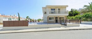 Ein zweistöckiges Wohnhaus mit Balkon, geschlossenem Eingangsbereich und gepflasterter Auffahrt.