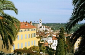 A coastal town with a prominent church tower, colorful buildings, and palm trees. - Beautiful guest house 60 M², 3*, in a quiet place with trees, closed property (Grasse)