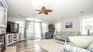 Ein Wohnzimmer mit Fernseher, Sofa, Couchtisch und Deckenventilator.