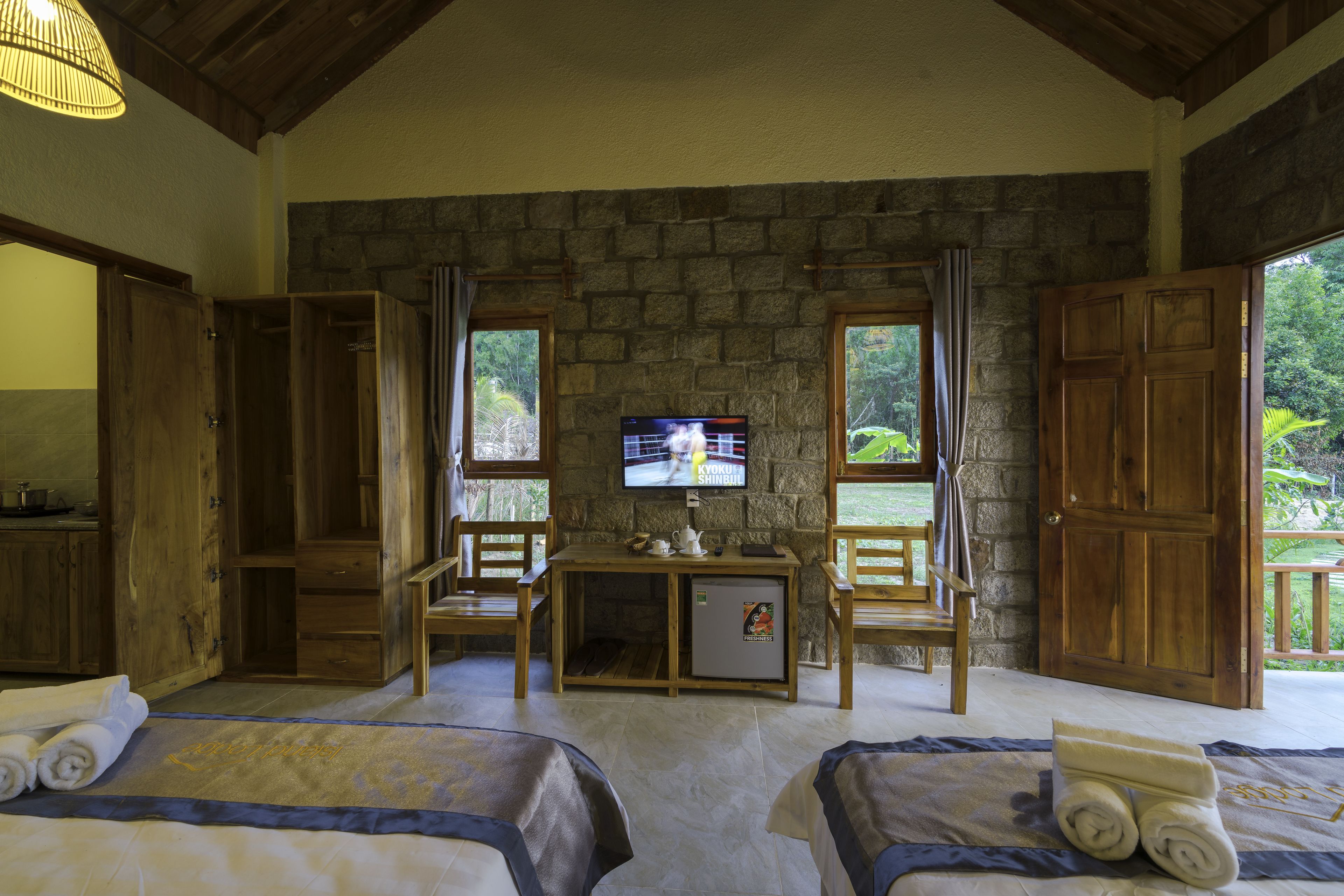 Ein Zimmer mit Holzmöbeln, einem Fernseher und einer Steinwand.