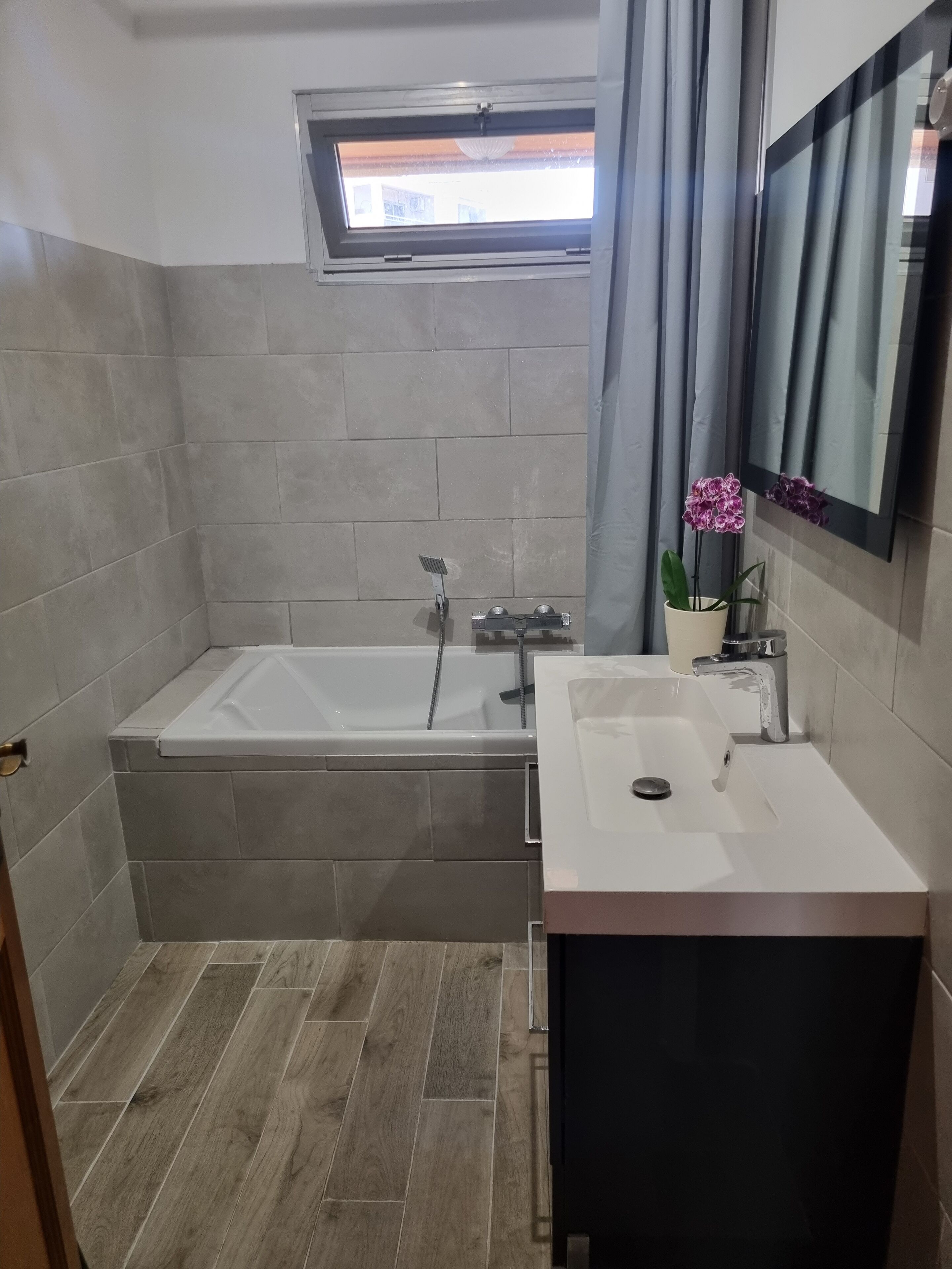 A bathroom with a bathtub, a sink, and a window.