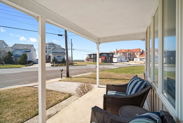 Relax on the covered porch with wicker furniture and enjoy the view of the quiet neighborhood.