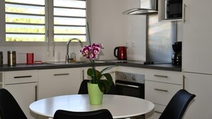 A modern kitchen with white cabinets, a stainless steel range hood, a microwave, and a coffee maker. - ARAUCARIA charming accommodation with swimming pool 2 to 4 people (Terre Sainte)