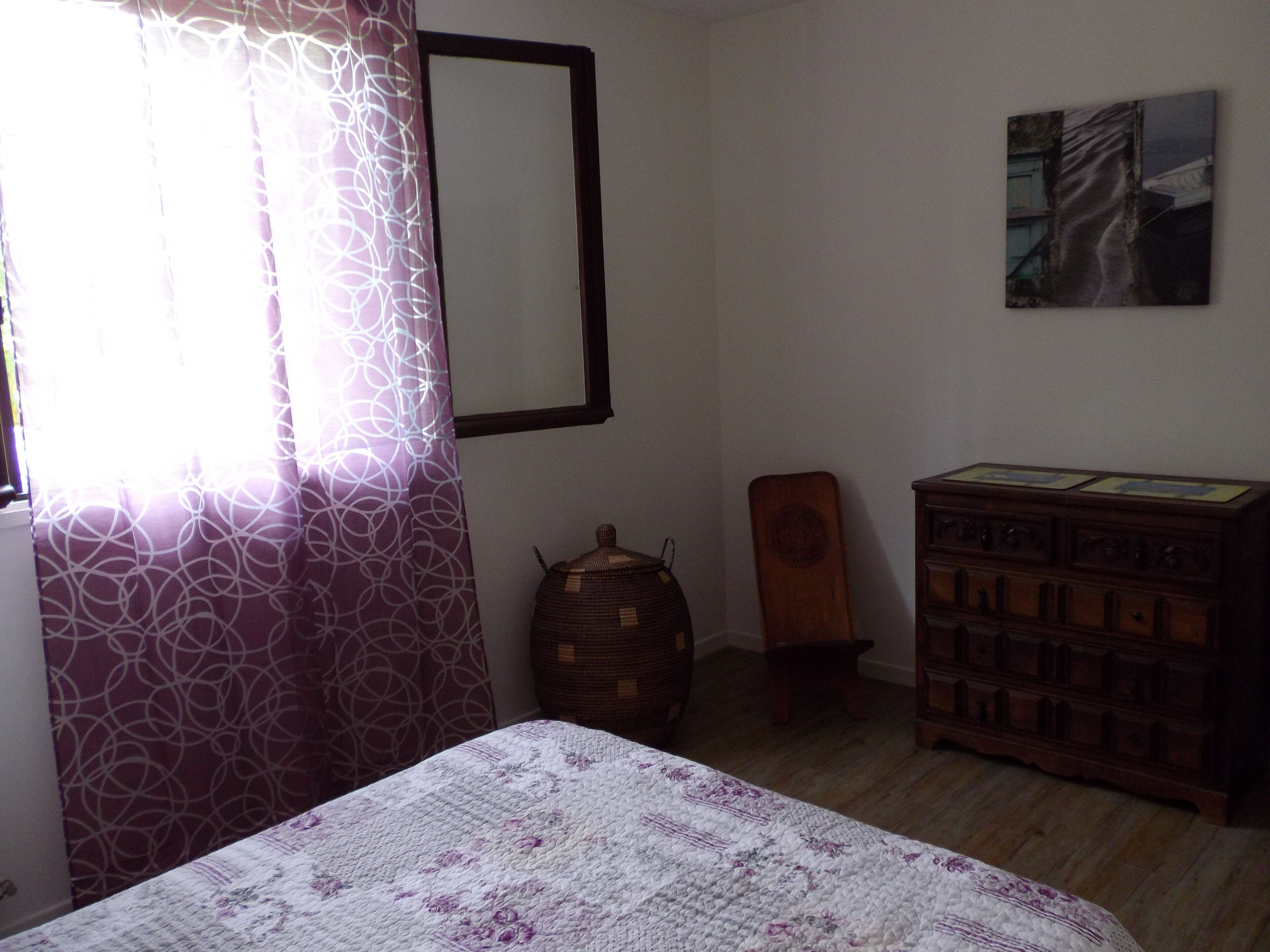 A bedroom with a bed, a dresser, a chair, and a painting on the wall.